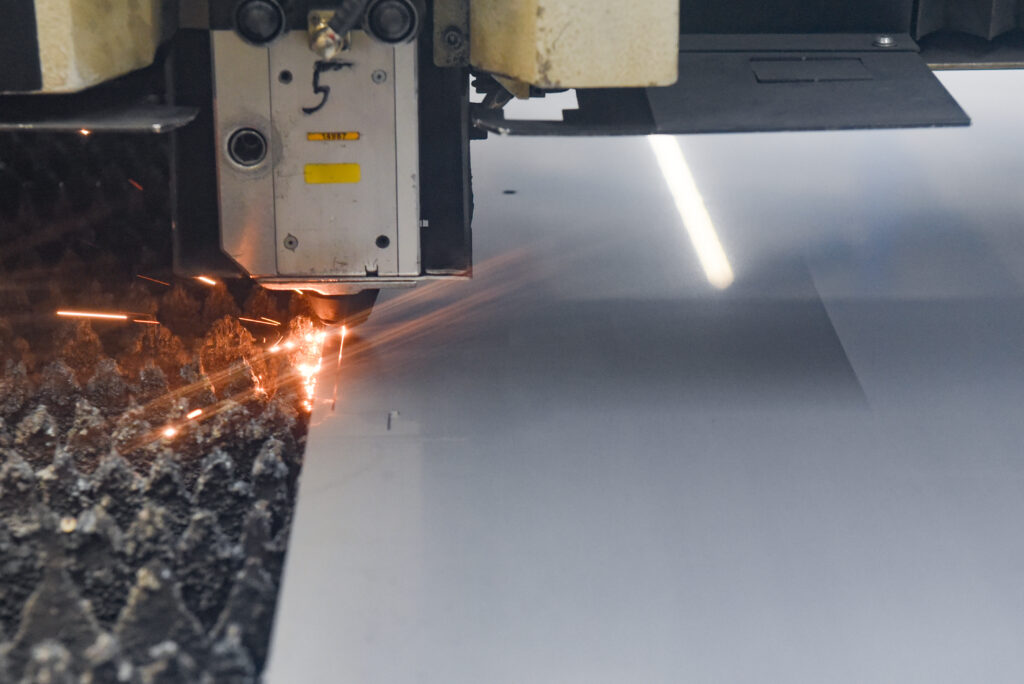 Laser schneidet präzise eine Metallplatte, Funken fliegen bei der Metallbearbeitung.